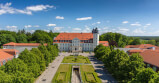 Großes Gebäude mit rotem Dach und weißem Turm umgeben von Bäumen unter bewölktem Himmel