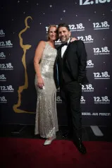 A man and woman smiling in formal attire, posing for a picture at 12.18. Investment Management GmbH premises