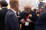 Zwei Männer in Anzügen unterhalten sich bei der MAK EXPO REAL, Event hervorgehoben von Gregor Voltje.