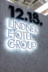 Schild an einer Wand mit Text '12.18, LINDNER, OTEL, GROUP'