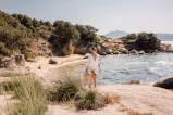 Frau spaziert am Strand, umgeben von Natur und Wasser, Urlaubsstimmung